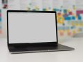 A laptop on a white table with a blurred background featuring colorful note papers.